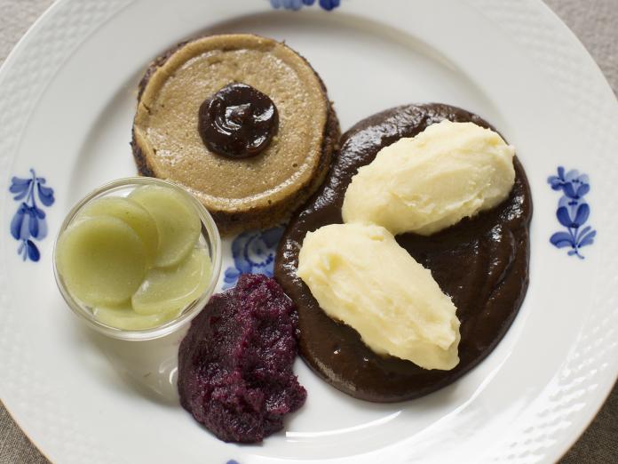 En anretning på en tallerken med gratineret rullesteg, kartofler og rødkål.